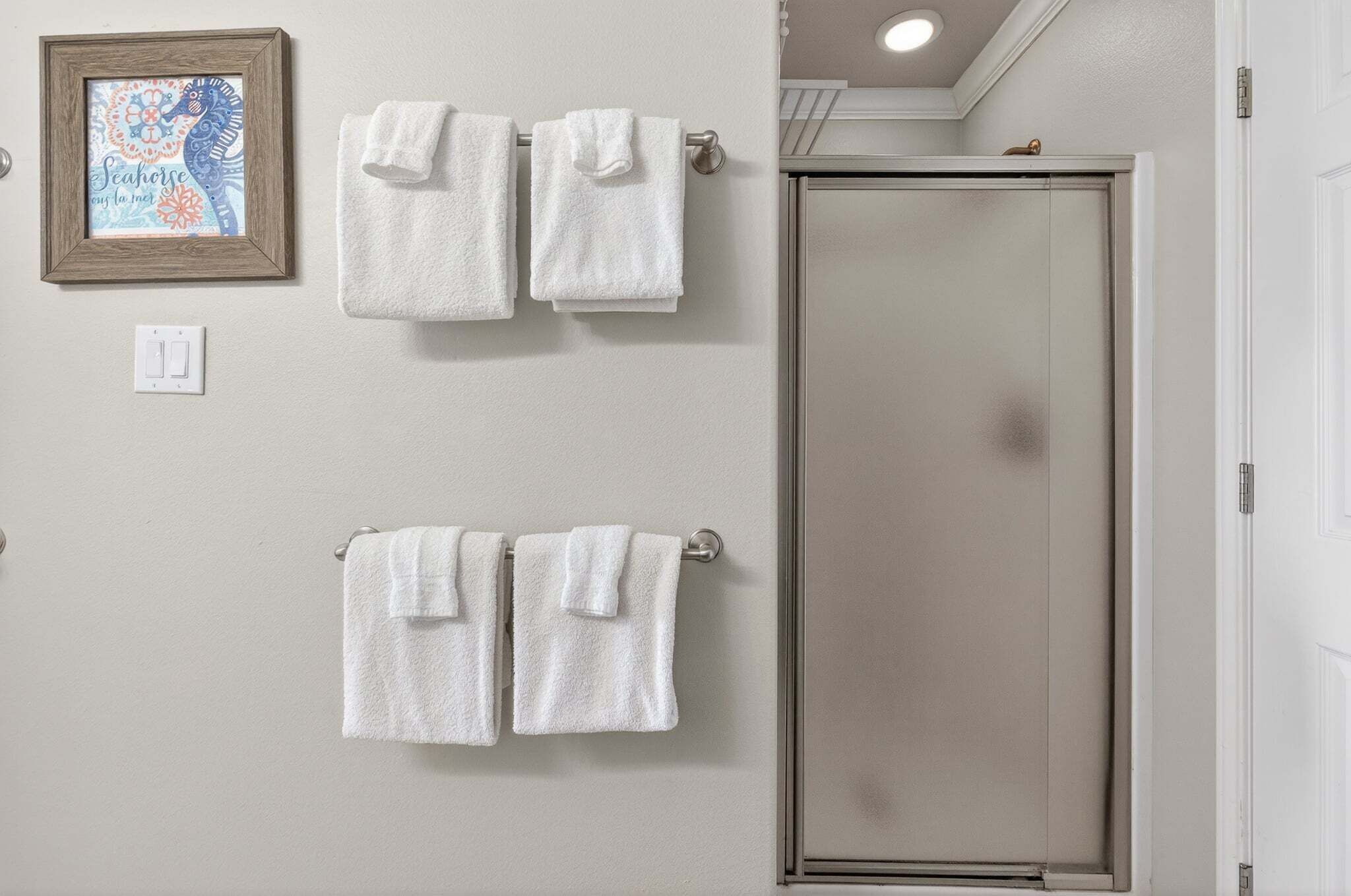 A bathroom with two towel racks, a framed artwork, and a closed door.