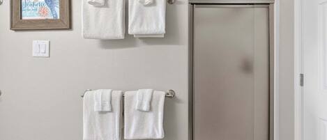 A bathroom with two towel racks, a framed artwork, and a closed door.