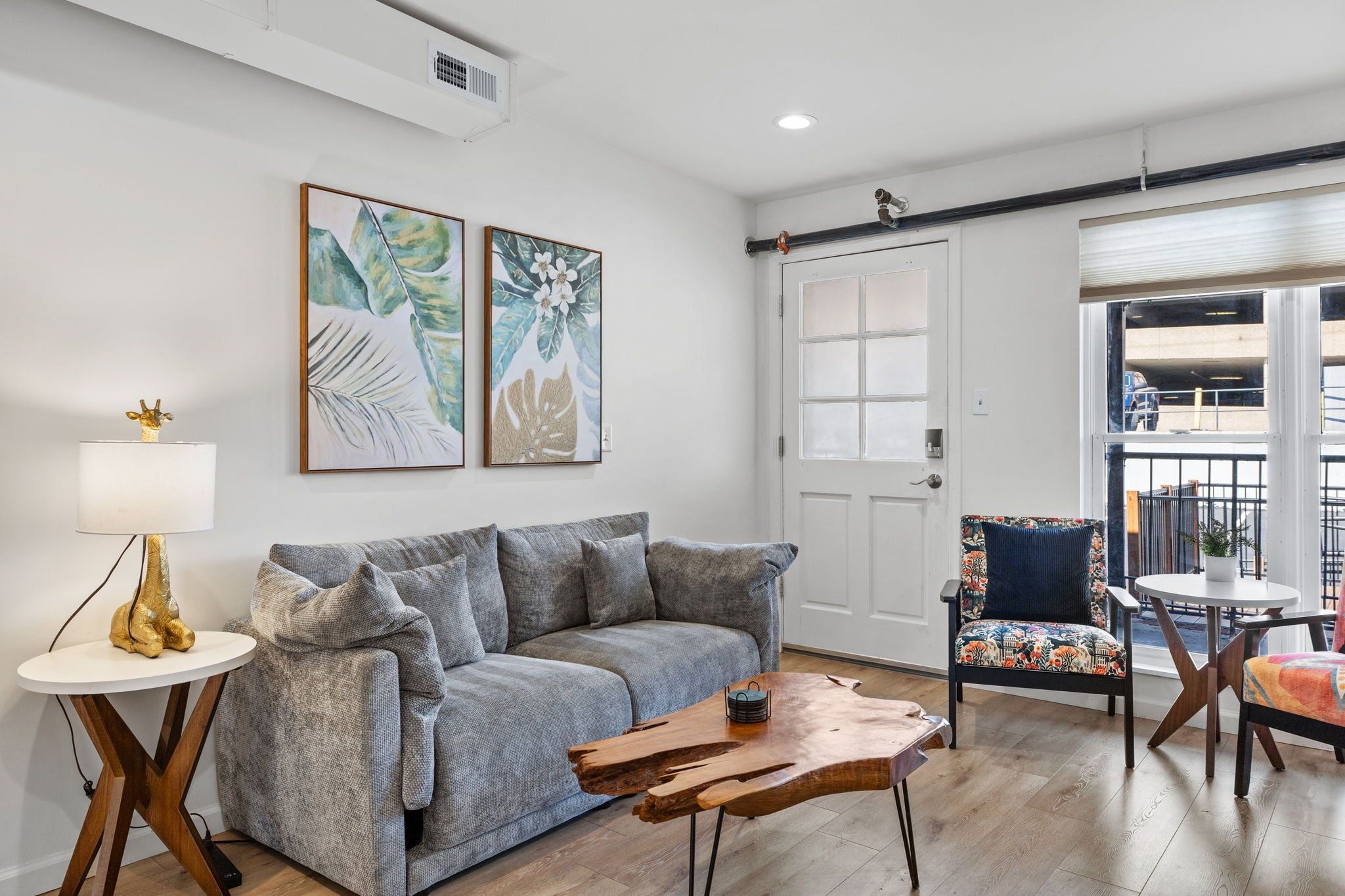 A living room with a grey sofa, a coffee table, a chair, and two wall-mounted paintings.