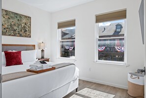 Bedroom with a made bed, bedside lamps, and two windows. - Main Street 2BR - Walk to Dining & Riverfront (Saint Charles)