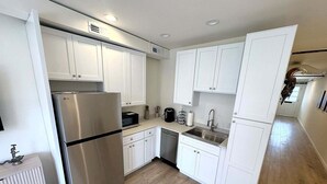 Una cocina moderna con armarios blancos, electrodomésticos de acero inoxidable y piso de madera.