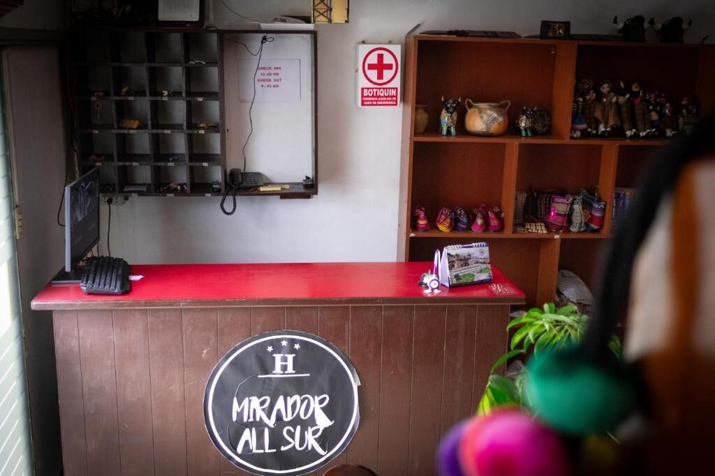 Una recepción con un cartel que dice 'Mirador All Sur', una barra roja, una estantería con objetos decorativos y un letrero que dice 'Bottiquin'.