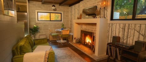 Una sala de estar acogedora con chimenea, comedor y sofá verde.