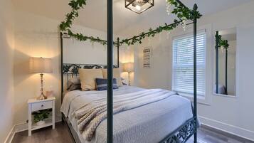 Ein Himmelbett mit Baldachin, Nachttischlampen, ein Nachttisch mit Pflanze und ein Spiegel an der Wand.