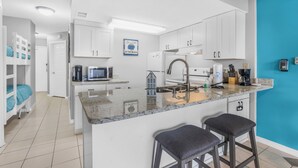 Een moderne keuken met witte kasten, een granieten werkblad en een blauwe accentmuur.
