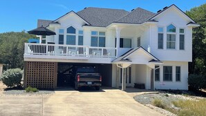 A two-story house with a covered garage, a balcony, and a driveway. - New Rental ~ Spacious Beach House - Hot Tub ~ Walk to the Beach (Kitty Hawk)