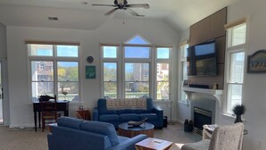 A spacious living room with a blue sofa, a wooden coffee table, and a fireplace. - New Rental ~ Spacious Beach House - Hot Tub ~ Walk to the Beach (Kitty Hawk)