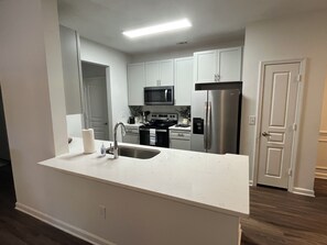 A modern kitchen with white cabinetry, stainless steel appliances, and a central island with a sink. -  Walk-in Spacious 3-bedroom apartment with AC in lovely Alpharetta (Alpharetta)