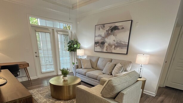 Un salon avec un canapé beige, une table basse ronde et un ventilateur de plafond.