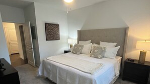 Une chambre à coucher avec un lit, des tables de chevet, un ventilateur de plafond et une porte.
