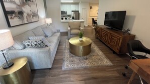 Un salon comprenant un canapé, une table basse, un téléviseur et un coin repas avec des chaises.
