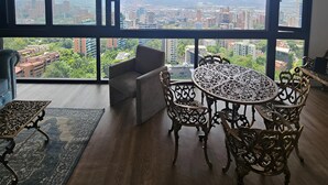 Ein Zimmer mit einem großen Fenster, einem runden Tisch mit Stühlen, einem Sofa und einem gemusterten Teppich.