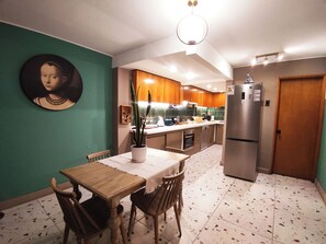 A kitchen with wooden cabinets, a dining table with chairs, a refrigerator, and a wall-mounted picture. - Huge apartment ideal for family and group travel, best location (Providencia)