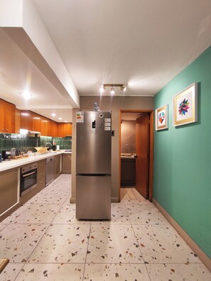 A modern kitchen with a stainless steel refrigerator, wooden cabinets, and a tiled floor. - Huge apartment ideal for family and group travel, best location (Providencia)