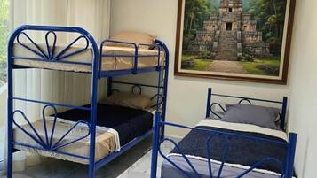 A room with bunk beds, a painting of a temple, and an air conditioning unit.