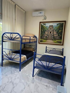 A room with bunk beds, a painting of a temple, and an air conditioning unit.