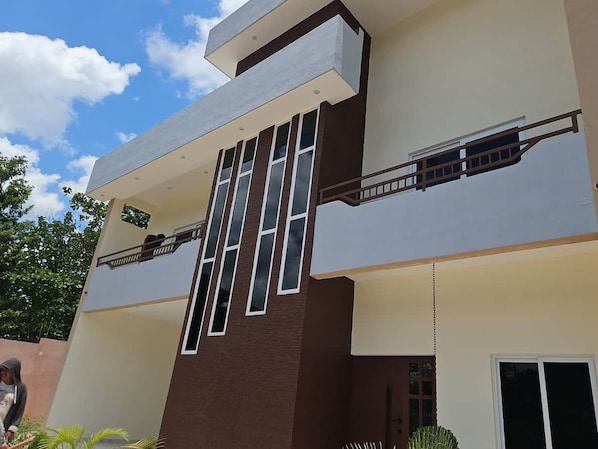 A modern building with a flat roof, large windows, and a balcony.