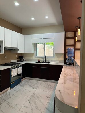 A modern kitchen with a built-in oven, a sink, and a window providing natural light.