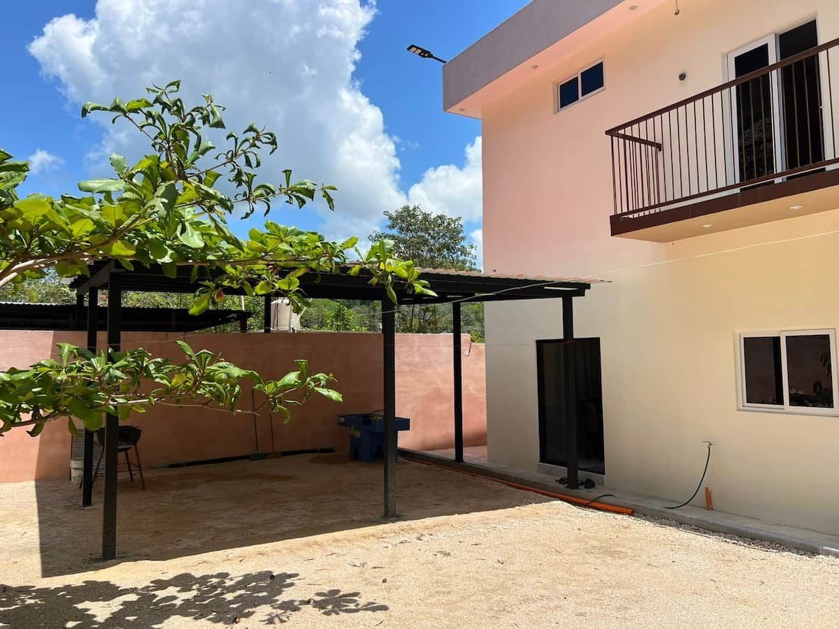 A covered outdoor area with a pergola, a TV mounted on the wall, and a balcony.