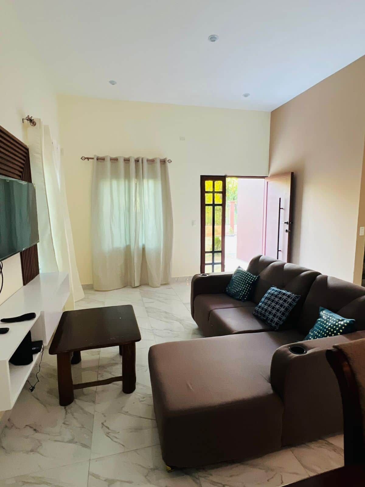 A living room with a sofa, a coffee table, and a television.
