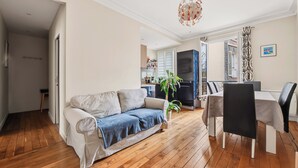 Een woonkamer met een bank, een eettafel, stoelen, een potplant en een televisie.