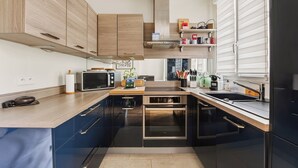 Een moderne keuken met houten kastjes, een ingebouwde oven en een raam met zonwering.