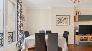 Een eetruimte met een tafel, stoelen en een televisie.