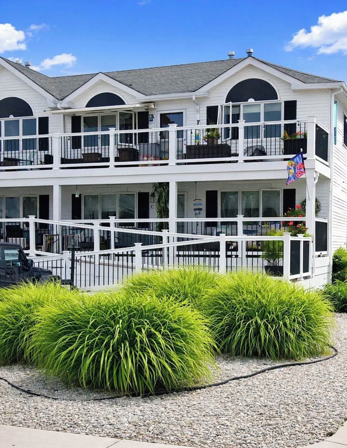 A multi-story hotel with balconies, a flag, and a gravel driveway.