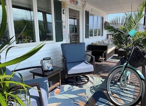 A covered porch with a blue chair, a small table, and a bicycle. - A Coastal Escape. 
Modern Marina district condo in delightful Wildwood (Wildwood)