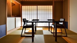Une pièce de style japonais traditionnel, avec un sol recouvert de tatamis, une porte coulissante de type shoji et un plafond bas doté d’un éclairage encastré.