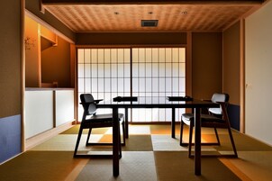 Una habitación japonesa tradicional con suelo de tatami, puerta corredera shoji e iluminación empotrada en el bajo techo.