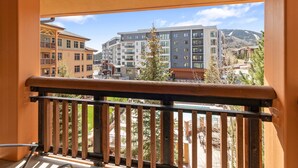 A balcony with a view of multi-story buildings, a mountain in the background, and a clear sky. - Sundial C302 | Ski-in/Ski-out | Fireplace | Mountain Views | Pool & Hot Tubs (Park City)