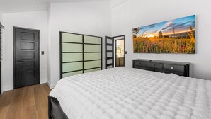 Un dormitorio con una cama, una puerta corredera, un aparador y un cuadro colgado en la pared.