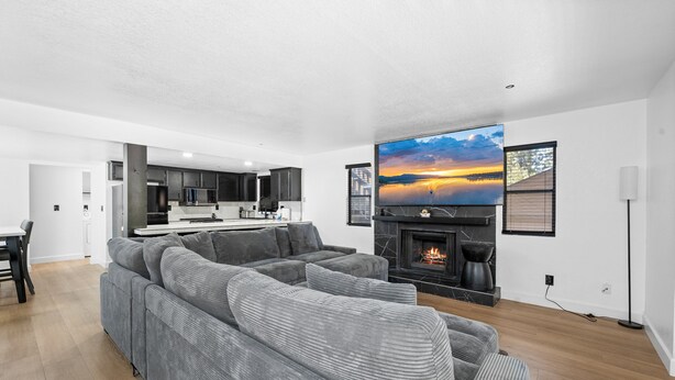 Una sala moderna con un sofá seccional gris grande, una chimenea y un televisor montado en la pared.