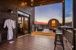 Una terrassa de fusta amb vistes a un capvespre, una sauna i una zona de bar.