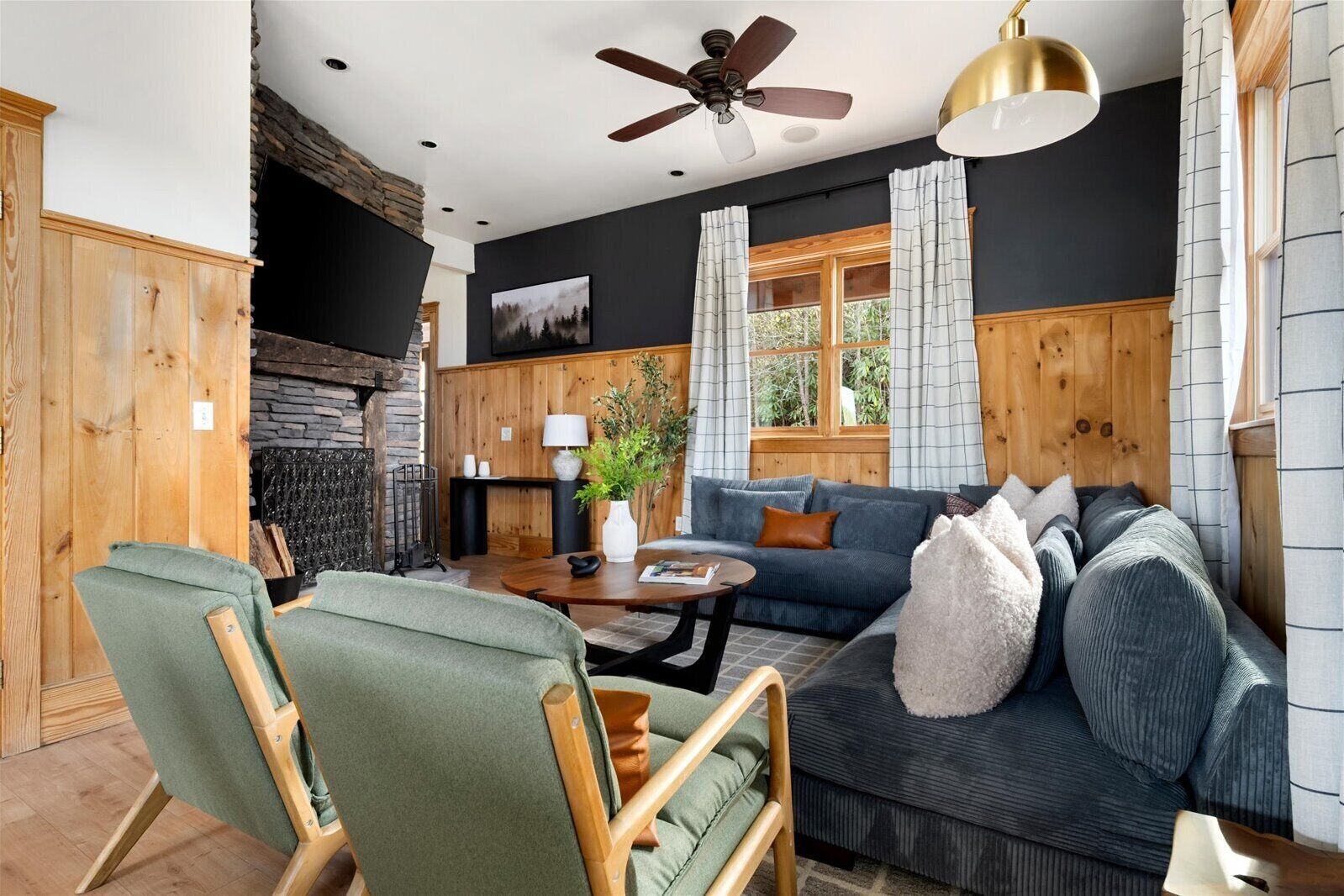 A cozy living room with a fireplace, wooden walls, a sofa, and a dining table.