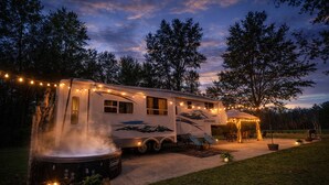 Ein stehender Wohnmobil mit Bergbild, einem Whirlpool und Lichterketten.