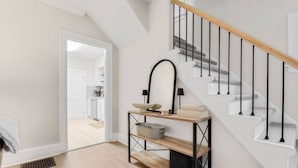 Een modern interieur met een trap, een keuken zichtbaar door een open deur en een houten vloer.