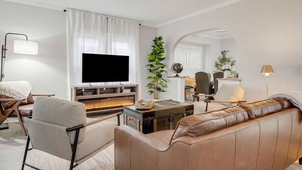 Een woonkamer met een televisie, bank, fauteuil, open haard en een wereldbol op een bureau.