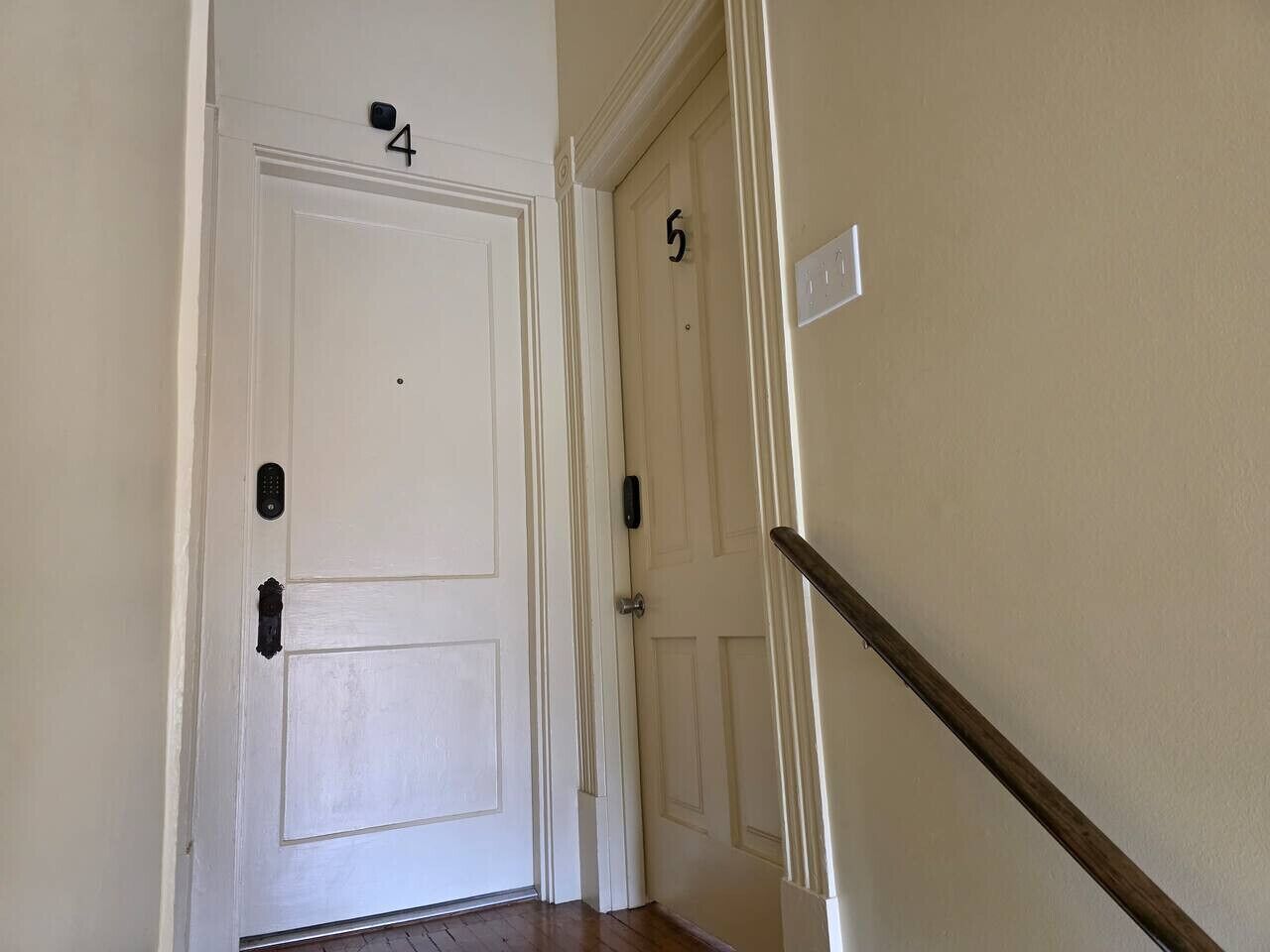 A hallway with two doors, numbered 4 and 5, and a wooden handrail.