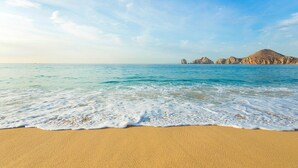 A beach with clear blue water and a sandy shore. - Cabo San Lucas oceanfront getaway with resort amenities (Cabo San Lucas)