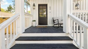 A porch with a black door, white railings, and a bench. - 🎥 Outdoor Movie Screen | Fire Pit | Games | Bikes | Sleeps 10 - Bike to Beach! (Inlet Beach)