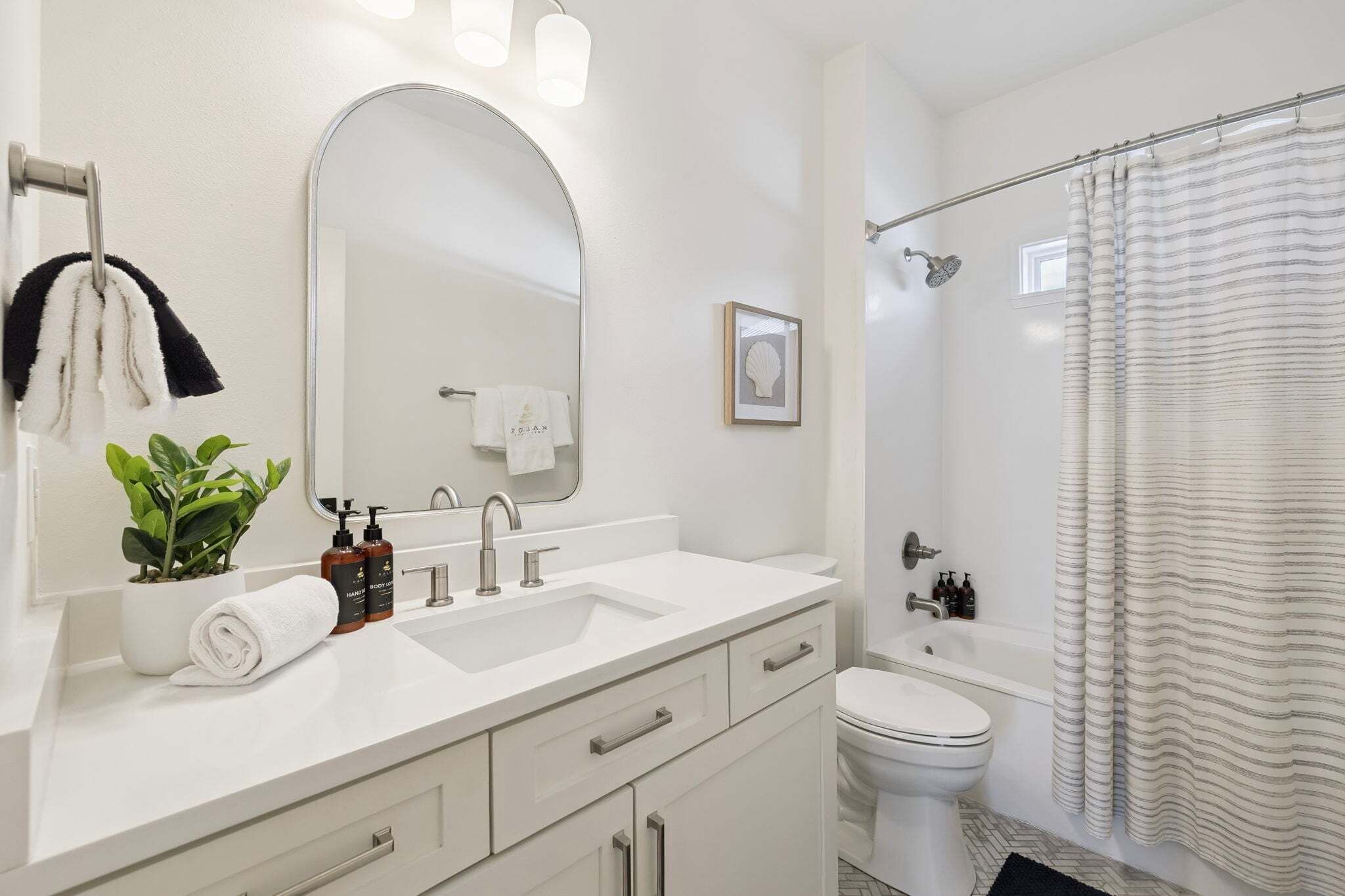 A modern bathroom with a white sink, mirror, and toilet.