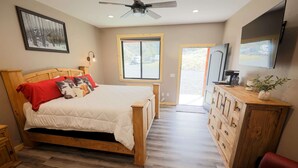 A bedroom with a wooden bed, a dresser, a television, and a window.