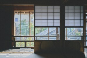 Ein traditioneller japanischer Raum mit Tatami-Böden, gleitenden Shoji-Schiebetüren und Blick auf eine Wohngegend.