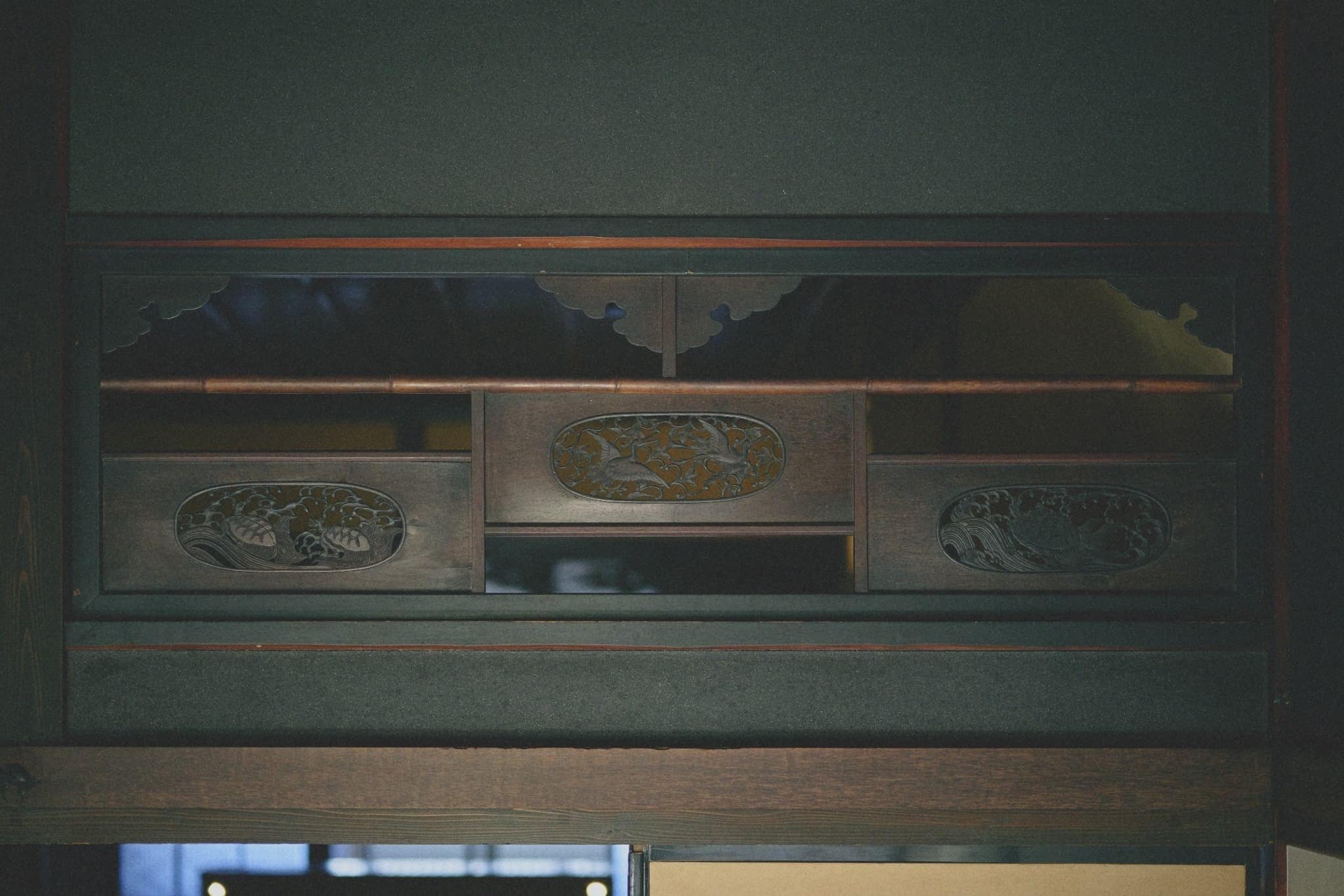 A wooden cabinet with intricate carvings and a central decorative panel.