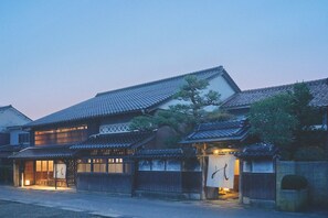 A traditional Japanese building with multiple wooden structures, a tiled roof, and a well-lit entrance. - KAZENO KURAYOSHI (Kurayoshi)