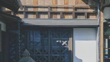 A traditional building with a wooden facade, large windows with lattice designs, and a stone lantern.