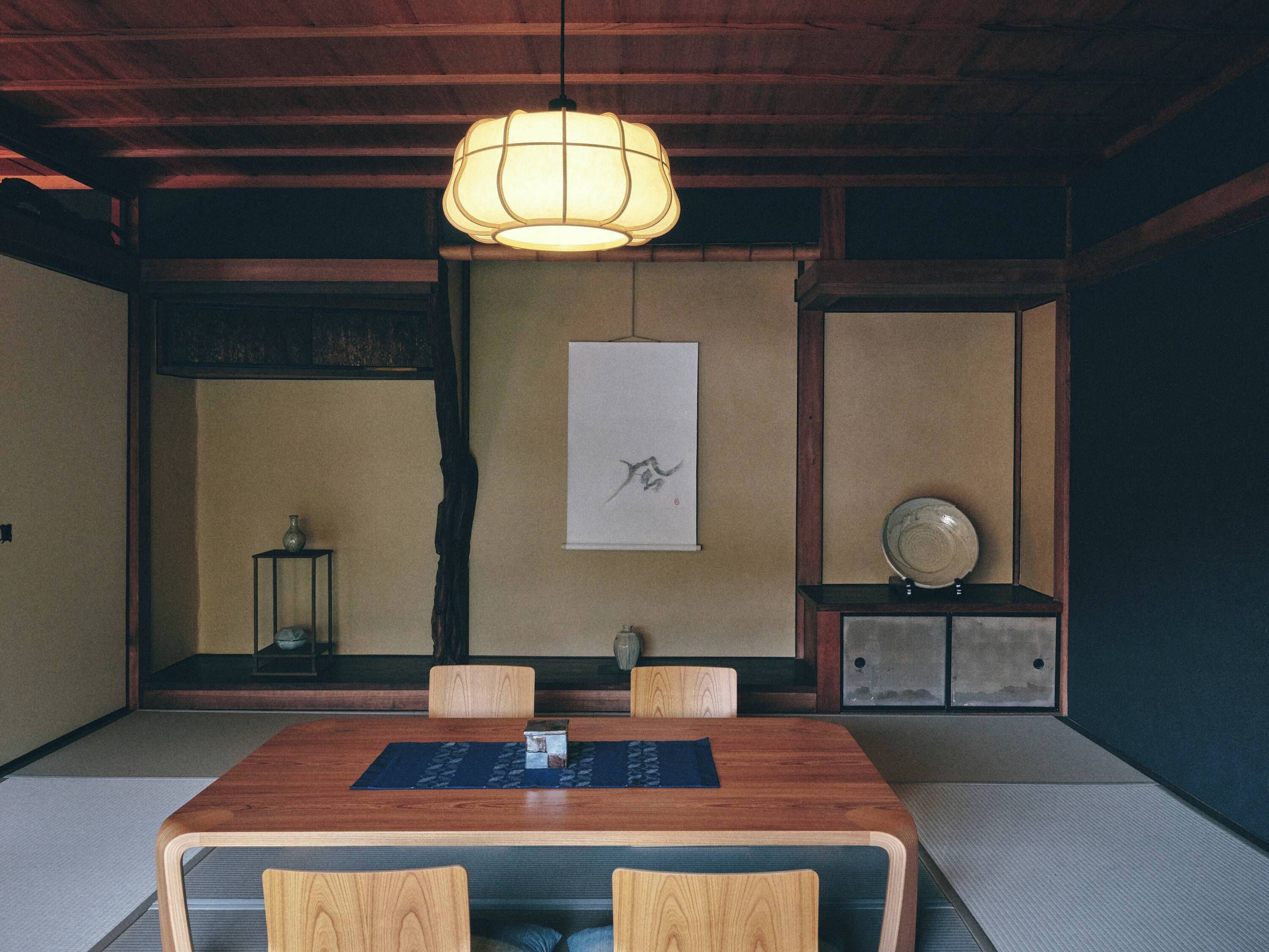 A traditional Japanese room with tatami flooring, a wooden dining table, and a hanging paper lantern.