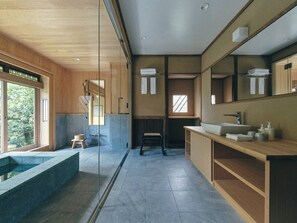 A modern bathroom with a large mirror, a built-in sink, and a shower area. - KAZENO KURAYOSHI (Kurayoshi)